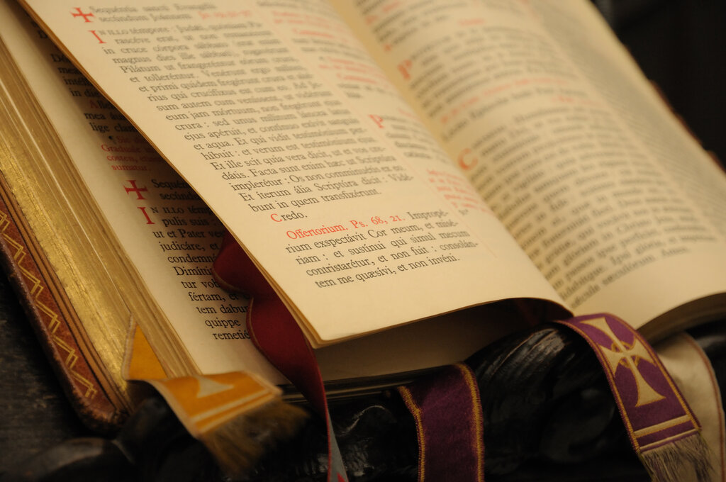 An open Missale Romanum showing Latin text with liturgical ribbons in purple and gold